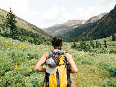 Woman hiking with a lunchbox and back back on 