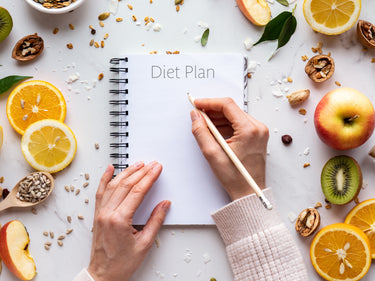 Diet plan woman writing in notebook with food surrounding her