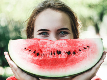 Happy smiling woman holding a slice of watermelon